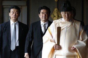 Japan's Prime Minister Shinzo Abe (C) is led by a Shinto priest as he visits Yasukuni shrine in Tokyo December 26, 2013. Abe visited Tokyo's Yasukuni Shrine for war dead on Thursday, in a move likely to anger Asian neighbour China and South Korea. REUTERS/Toru Hanai