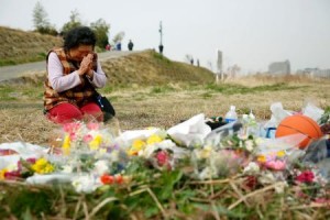 A woman lays flowers and prays at the site where Uemura's body was discovered.